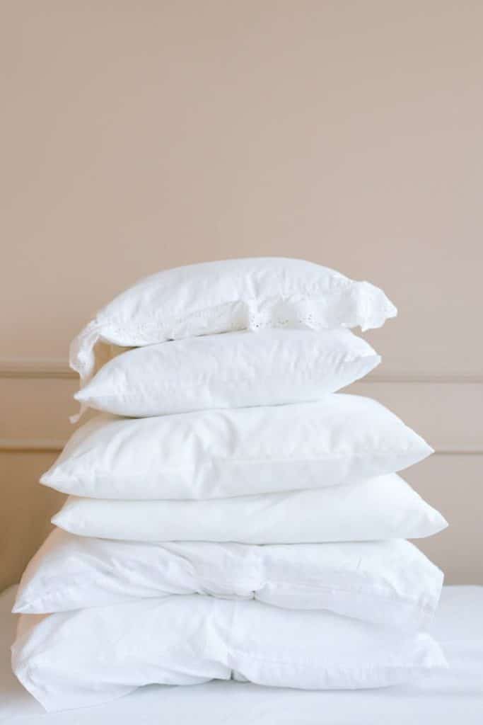 A stack of white pillows on a neutral background, showcasing elegance and simplicity.